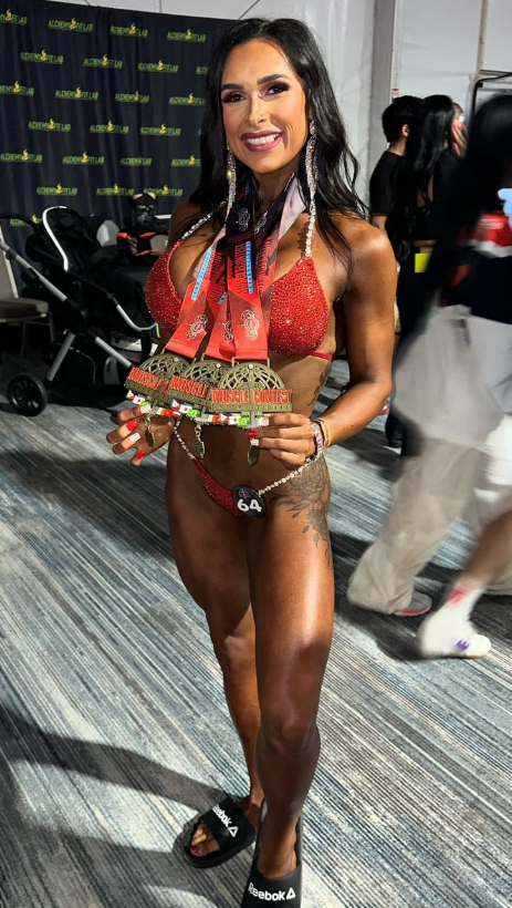 Sienna Vannoy holding championship medals at a bodybuilding competition